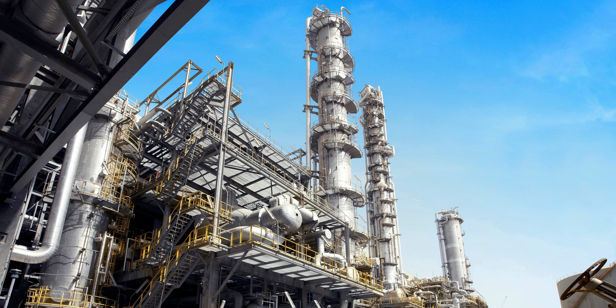 Distillation columns and pipework at a petrochemical plant under a clear sky